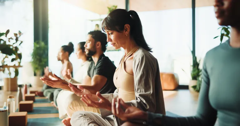 Group practicing mindfulness meditation in a bright studio
