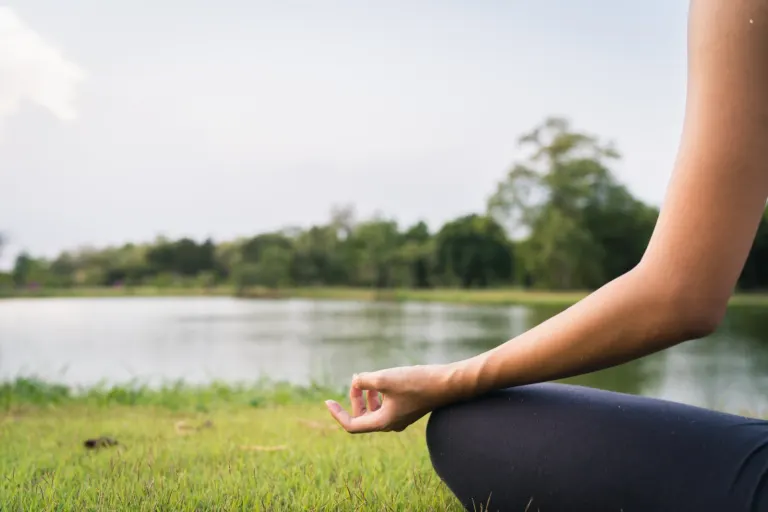 Woman practicing calm breathing by a lake — stress inoculation support at ZipHealthy Bentonville