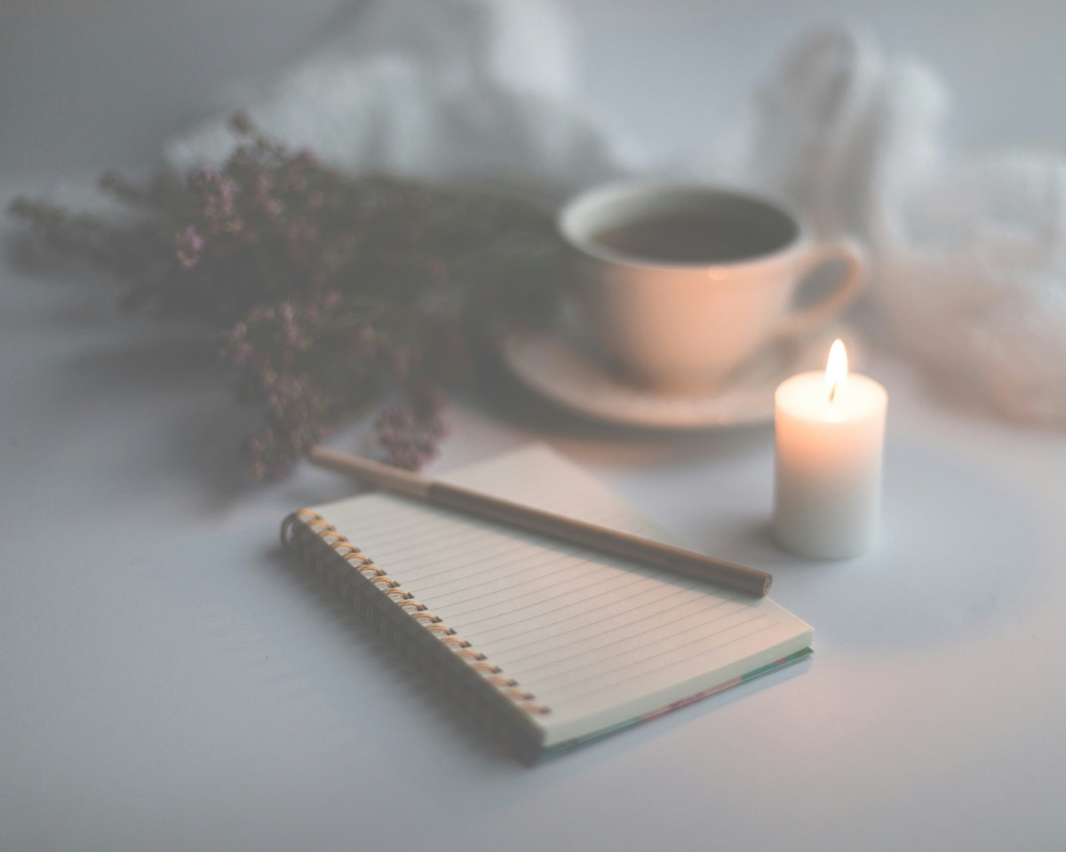 Wellness journaling setup with notebook, candle, and coffee